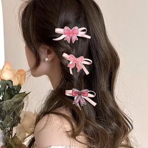 Three-piece set of pink embroidered butterfly bow hair clips worn on wavy brown hair