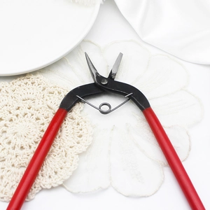 Detail of red-handled jewelry crafting scissors on white silk and lace background
