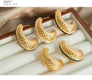 Detail of five pairs of hammered gold C-shaped earrings with colorful enamel edges