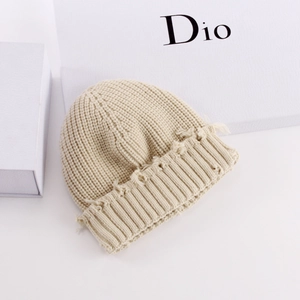 Detailed close-up of cream chunky knit beanie featuring trendy distressed fringe edges