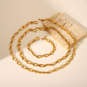 Detail view of gold geometric link necklace and bracelet set on a natural stone base