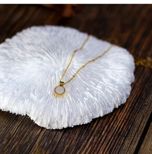 Macro detail of 18K gold plated round necklace with white mother of pearl inlay