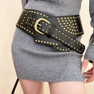 Detail of vintage leather belt with gold studs styled on a grey knitted dress
