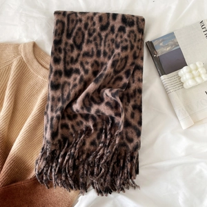 Close-up of leopard print scarf with fringe, cozy knit sweater and home decor