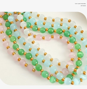 Macro detail of cat eye stone beads in green, pink, and blue with gold spacers necklace