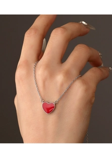 Close-up of red heart pendant necklace on hand showing delicate silver chain detail