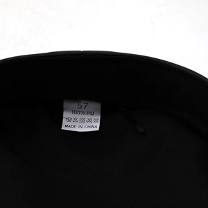 Detail view of cotton flat top cap showing size 57 label and 100% PU leather material