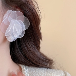 Detail of elegant white organza flower earrings with pearl accent on a female model