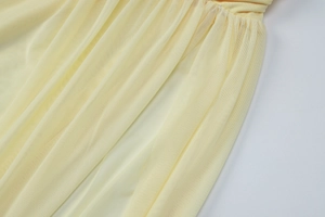 Detail shot of light yellow mesh fabric with delicate pleated texture and elegant drape