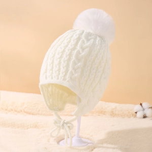 Detail of white knit baby hat with ear flaps, fluffy pompom and soft textured lining