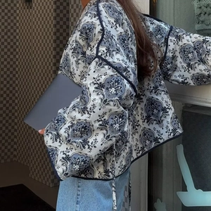 Lifestyle shot of woman in loose blue floral print jacket with dark navy trim