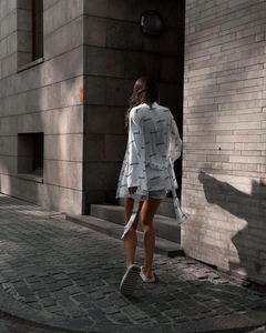 Outdoor street view of a white loungewear set with black letter prints and a waist tie