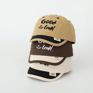 Close-up of stacked kids cotton baseball caps with Good Luck embroidery and side labels