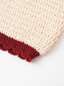 Detail of hollow-out knit pattern with cream and burgundy color-block ribbed edges