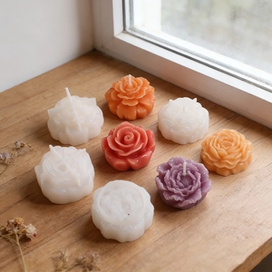 Candele profumate a forma di peonia in vari colori su un davanzale in legno