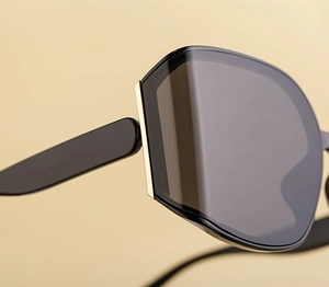 Close-up of black square sunglasses featuring detailed gold metal hinges and frame craft