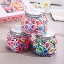 Three jars of colorful elastic cotton hair ties for kids in pastel pink and blue hues