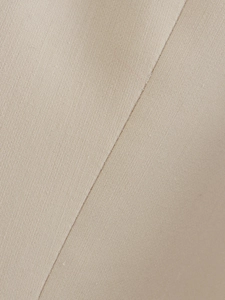 Macro shot of beige woven fabric texture with precise stitching detail on the pants