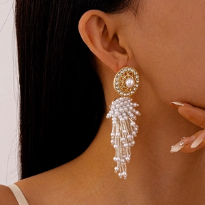 Détail de boucles d'oreilles dorées avec pampilles de perles et diamants sur un mannequin