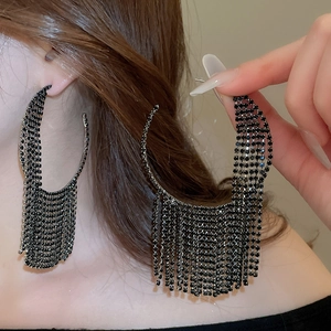 Close-up of oversized black rhinestone tassel earrings with geometric circular design