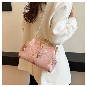 Detail of pink embroidered silk handbag with floral patterns and luxury pearl strap