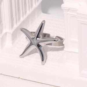 Detailed view of starfish silver open ring on white column with polished metal finish