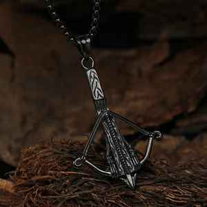 Macro shot of retro stainless steel crossbow pendant with detailed engravings on black chain