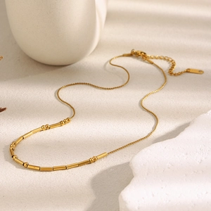 Minimalist 18K gold plated stainless steel snake chain necklace with beads on beige surface