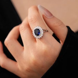 Detailed close-up of a royal blue oval sapphire ring with sparkling white zircon halo