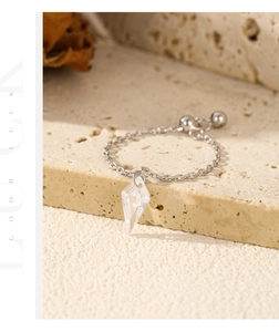 Detail of adjustable S925 silver chain ring with clear crystal pendant on beige stone