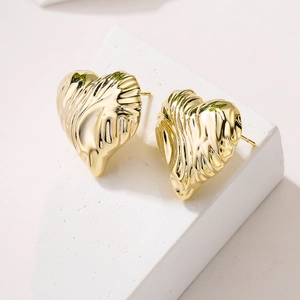 Polished gold plated geometric heart stud earrings with unique textured finish on a stone base
