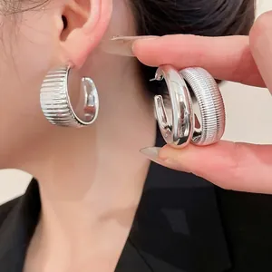 Polished silver C-shaped hoop earrings with split smooth and textured ribbed design