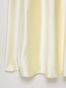 Detailed close-up of smooth cream yellow satin fabric with high gloss and elegant drape