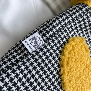 Détail du tissu pied-de-poule noir et blanc avec fourrure jaune et étiquette de marque