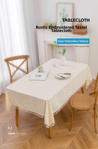 Detail of cream rectangle tablecloth featuring daisy embroidery and fine tassel edges