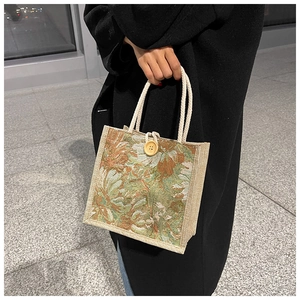 Detail showing natural jute floral fabric texture and round wooden button on the handbag