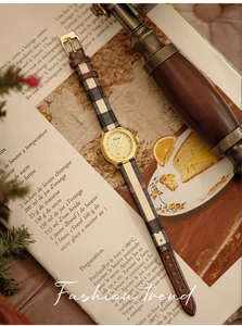 Detail of vintage gold hexagonal watch with leather and checkered strap on a retro book