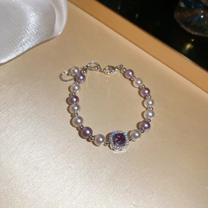 Detail of zircon manta rose pearl bracelet with square purple gemstone on silk