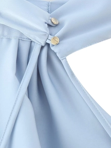 Detail of light blue satin dress featuring a fine seam and a round gold metal button