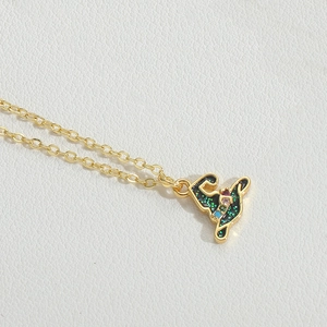 Close-up of golden necklace with black enamel and colored crystals on white leather