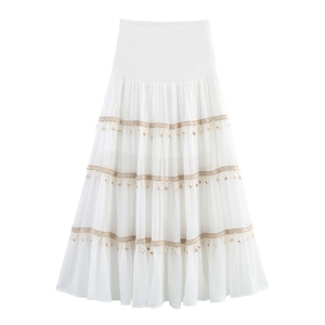 Detail of bohemian white tiered skirt featuring elastic waist and hanging seashell charms