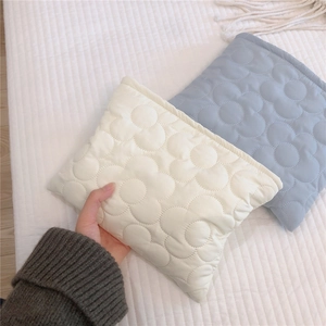 Detail view of cream and blue quilted storage bags with floral stitching and soft padding