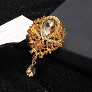 Detailed close-up of golden crown brooch with champagne crystals on black velvet