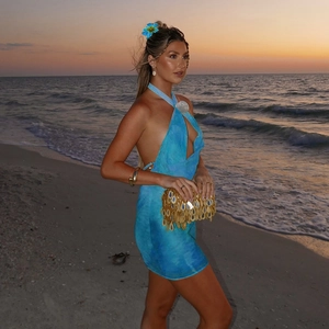 Detail of blue tie-dye halter backless mini dress worn on a beach at sunset