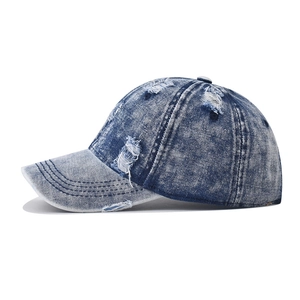 Detailed close-up of distressed washed denim baseball cap with vintage frayed holes