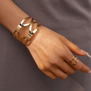 Gros plan d'un ensemble bracelet et bague ajourés en métal doré pour femme sur mannequin