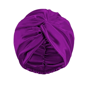 Dettaglio del turbante in raso viola con trama setosa e design frontale incrociato