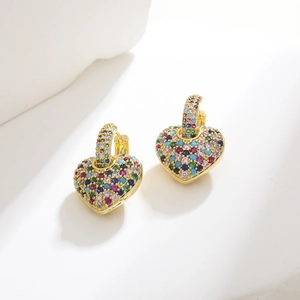 Macro view of gold heart earrings with multi-color zircon stones on white background