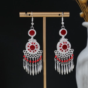 Detail of silver bohemian earrings with red beads and hanging fringe on display
