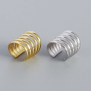 Macro detail of multi-layer gold and silver ear cuffs with a minimalist line design